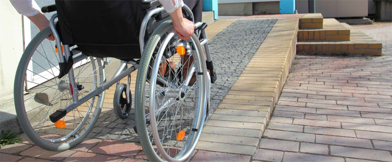 Un hombre en silla de ruedas delante de una rampa.