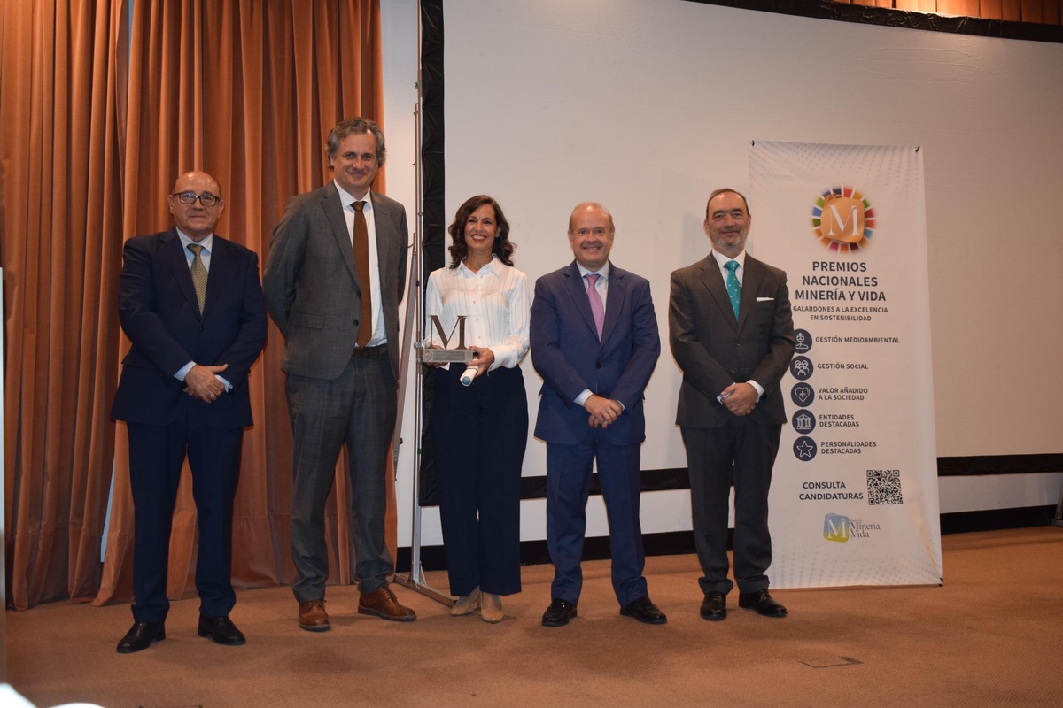 Cinco asistentes posan con el galardón de Knauf junto al cartel de los Premios Nacionales Minería y Vida.