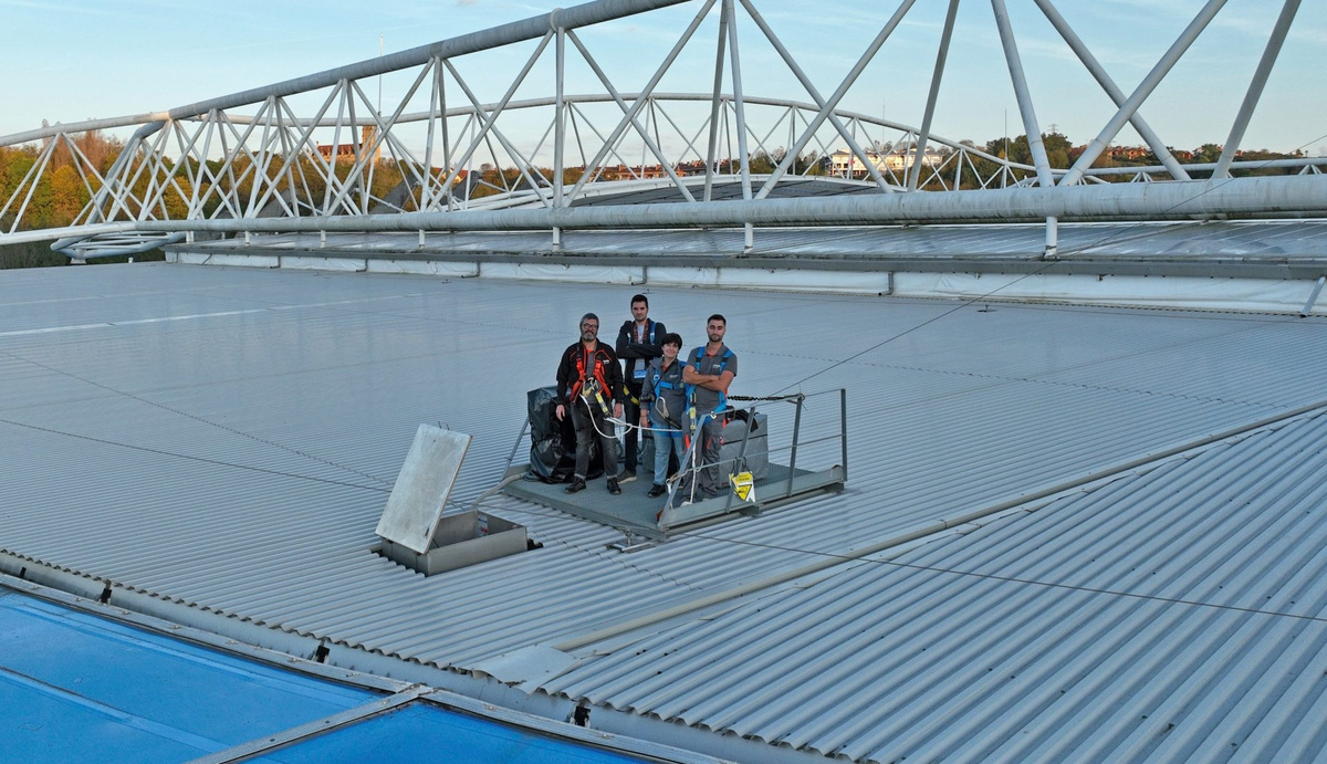 Cuatro técnicos con equipos de seguridad sobre la cubierta del estadio de Anoeta, junto a su estructura metálica.